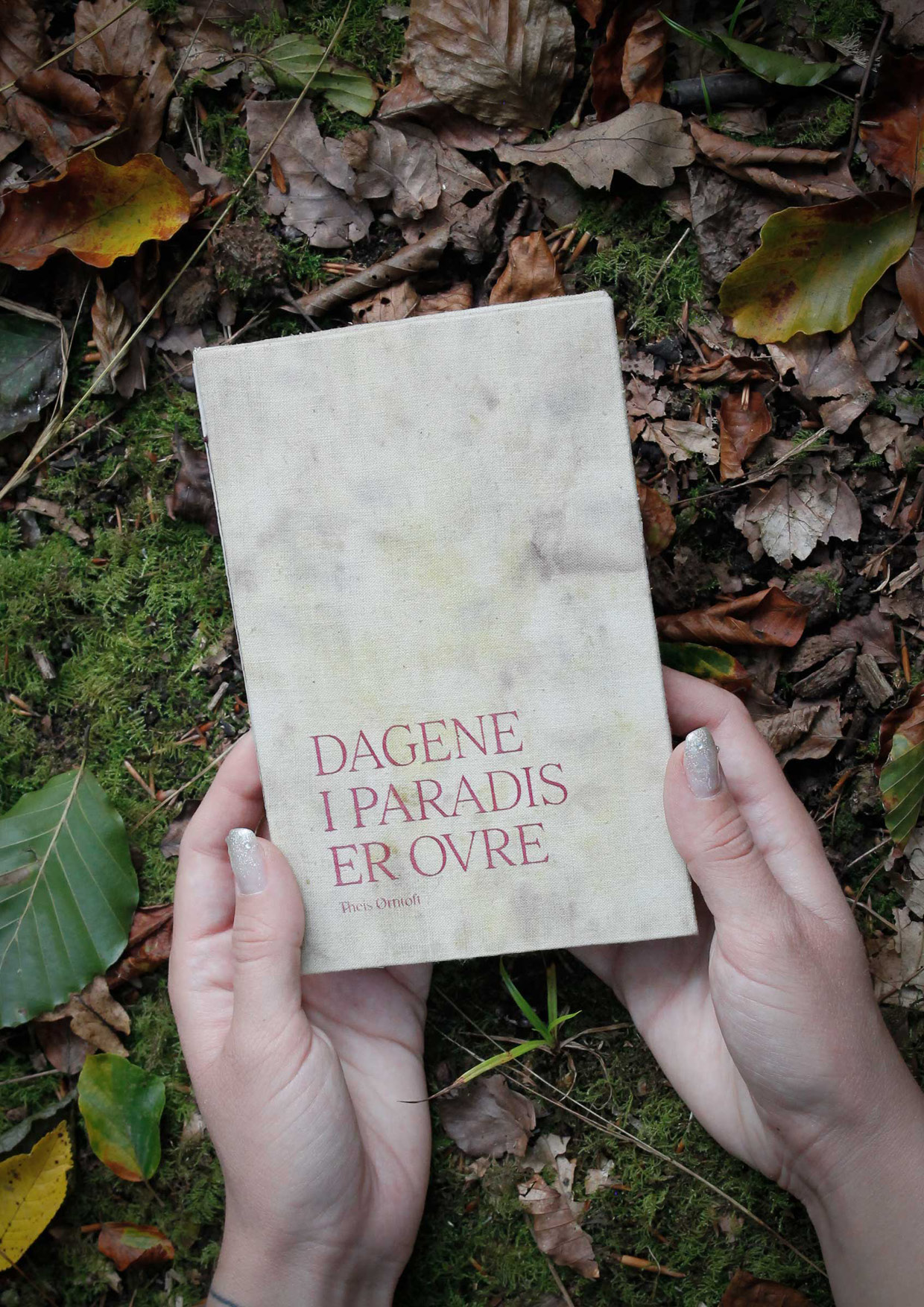 A book bound with handdyed fabric lying in a forest.