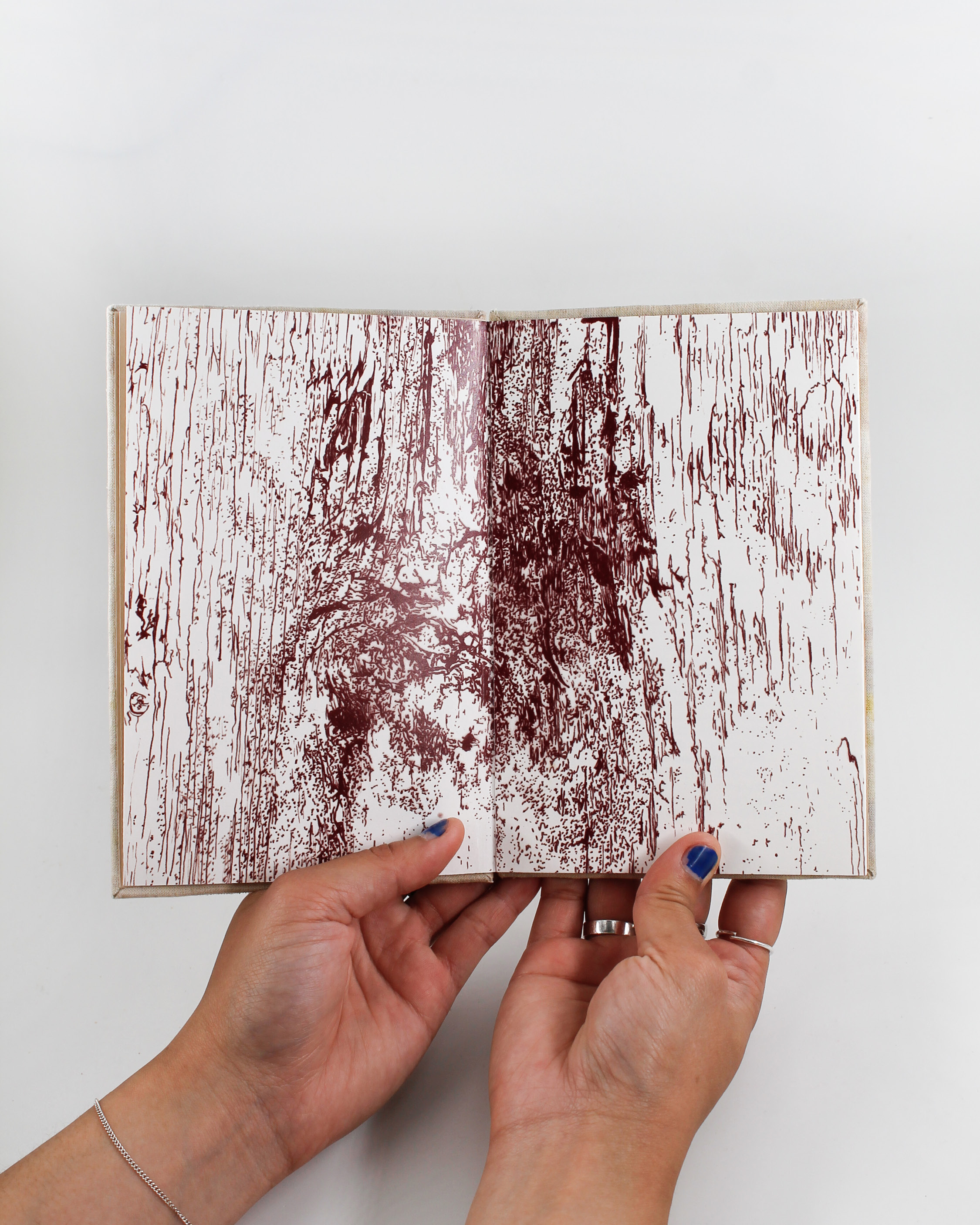 Open book with a big detailed fineliner illustration of wood in dark red.