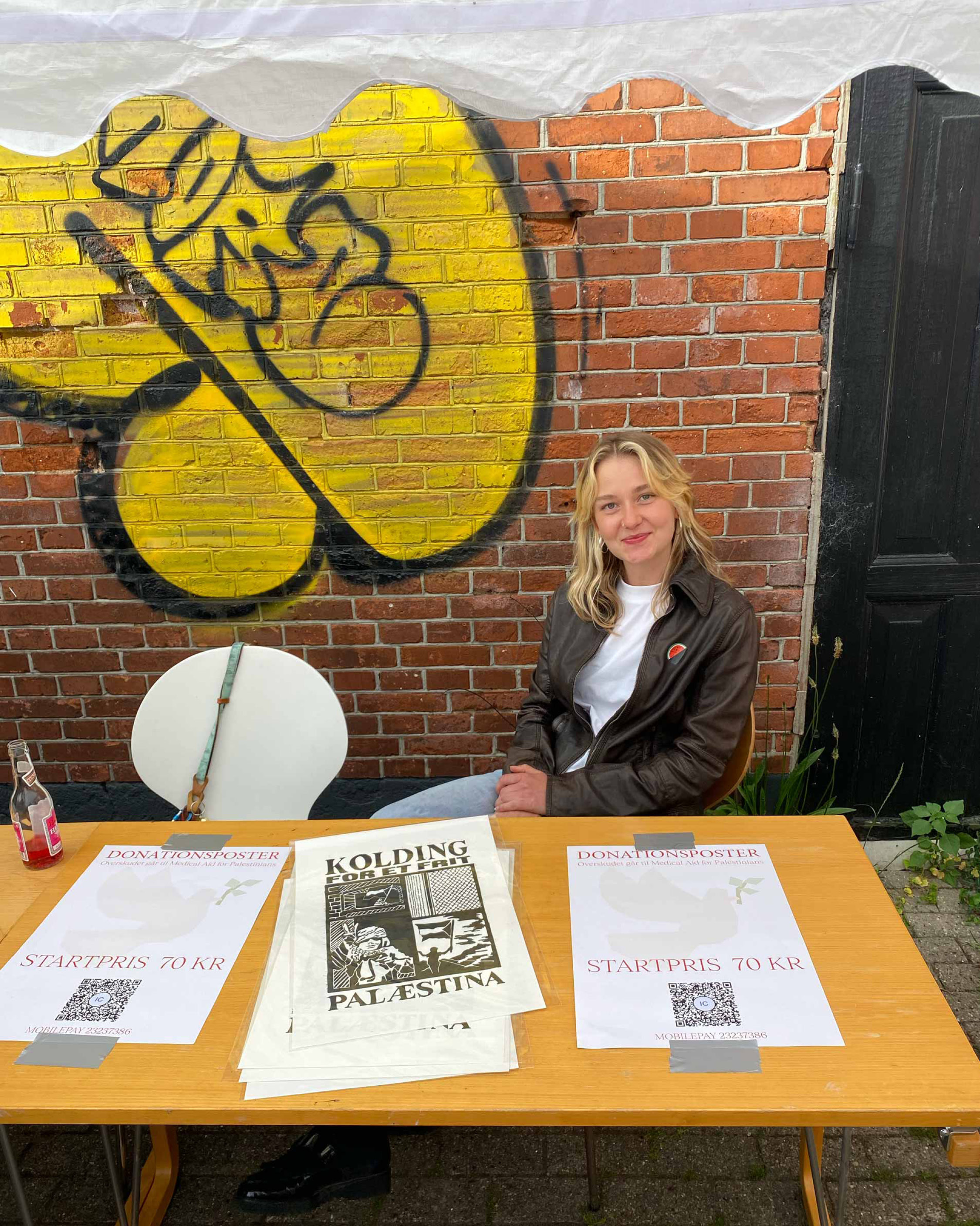 Girl sitting at a table selling linoprints.